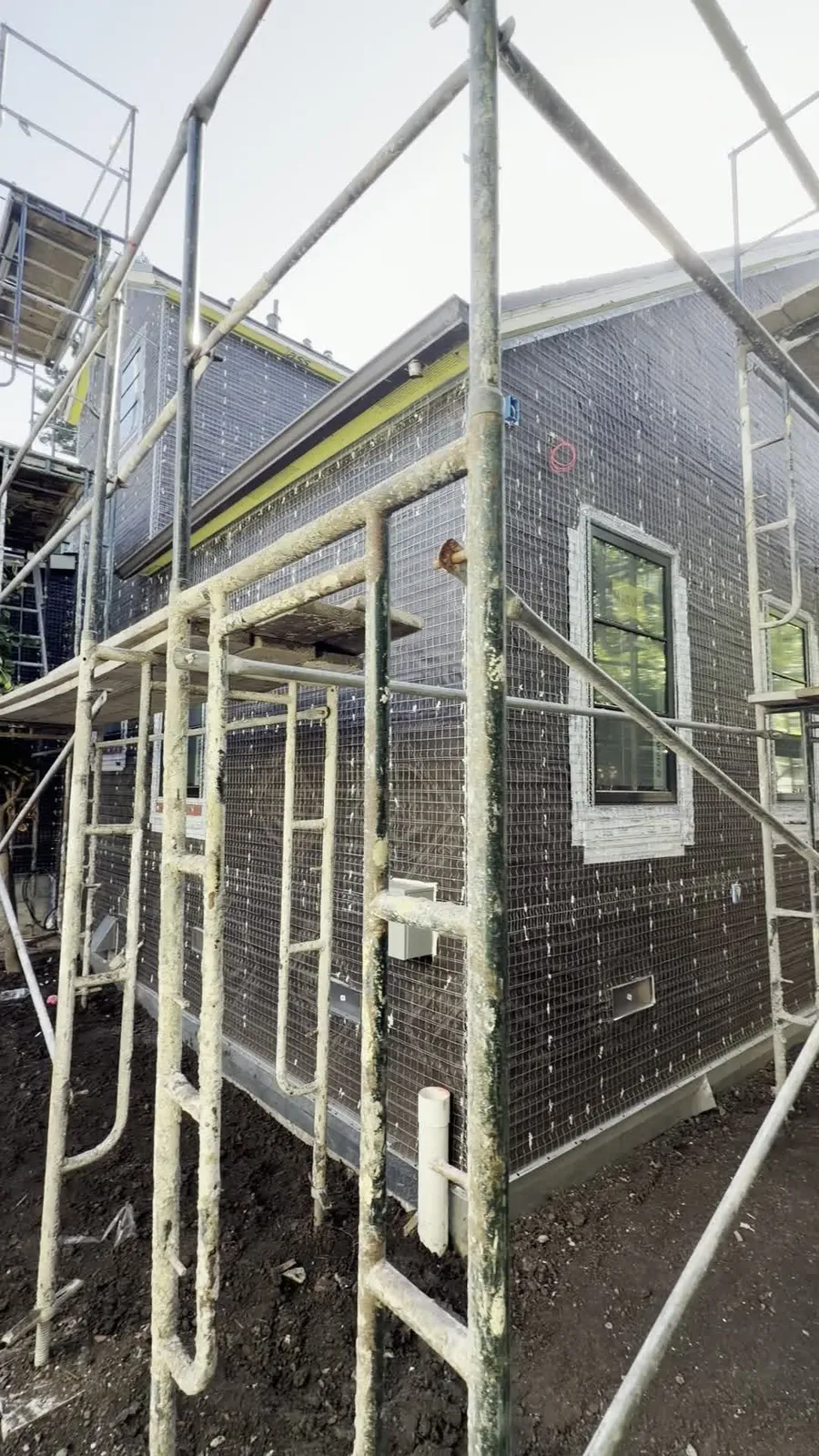Wire lath and weather barrier installed behind scaffolding